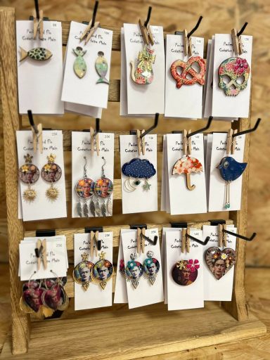 Une étagère en bois avec divers bijoux colorés accrochés sur des cartes.