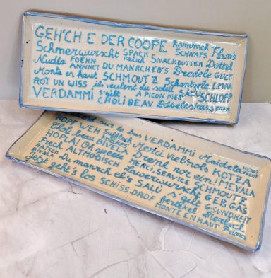Plaques en céramique avec inscriptions manuscrites en bleu sur fond crème.