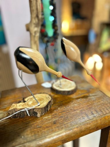 Deux sculptures de oiseaux en bois sur une table en bois.