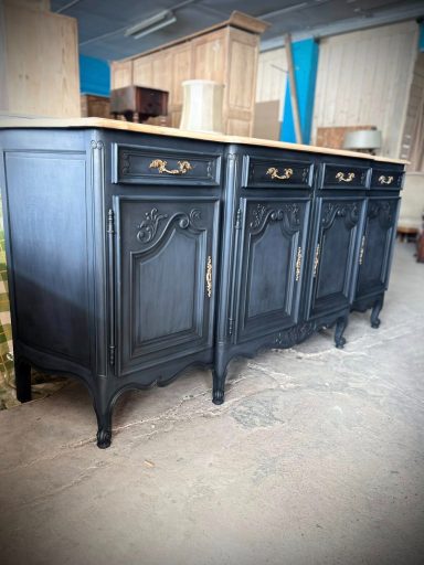 Buffet en bois noir avec plusieurs tiroirs et poignées dorées.